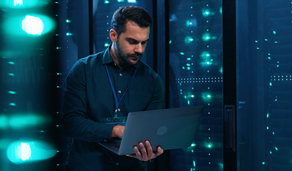 Man in data center checks current system status on his laptop