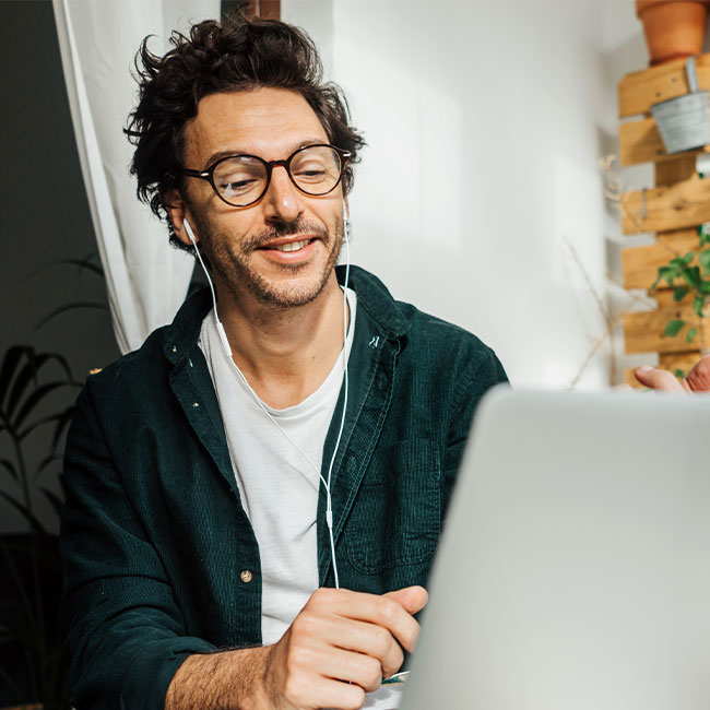 Mann sitzt zuhause vor seinem Laptop und nimmt an einer Online-Veranstaltung teil